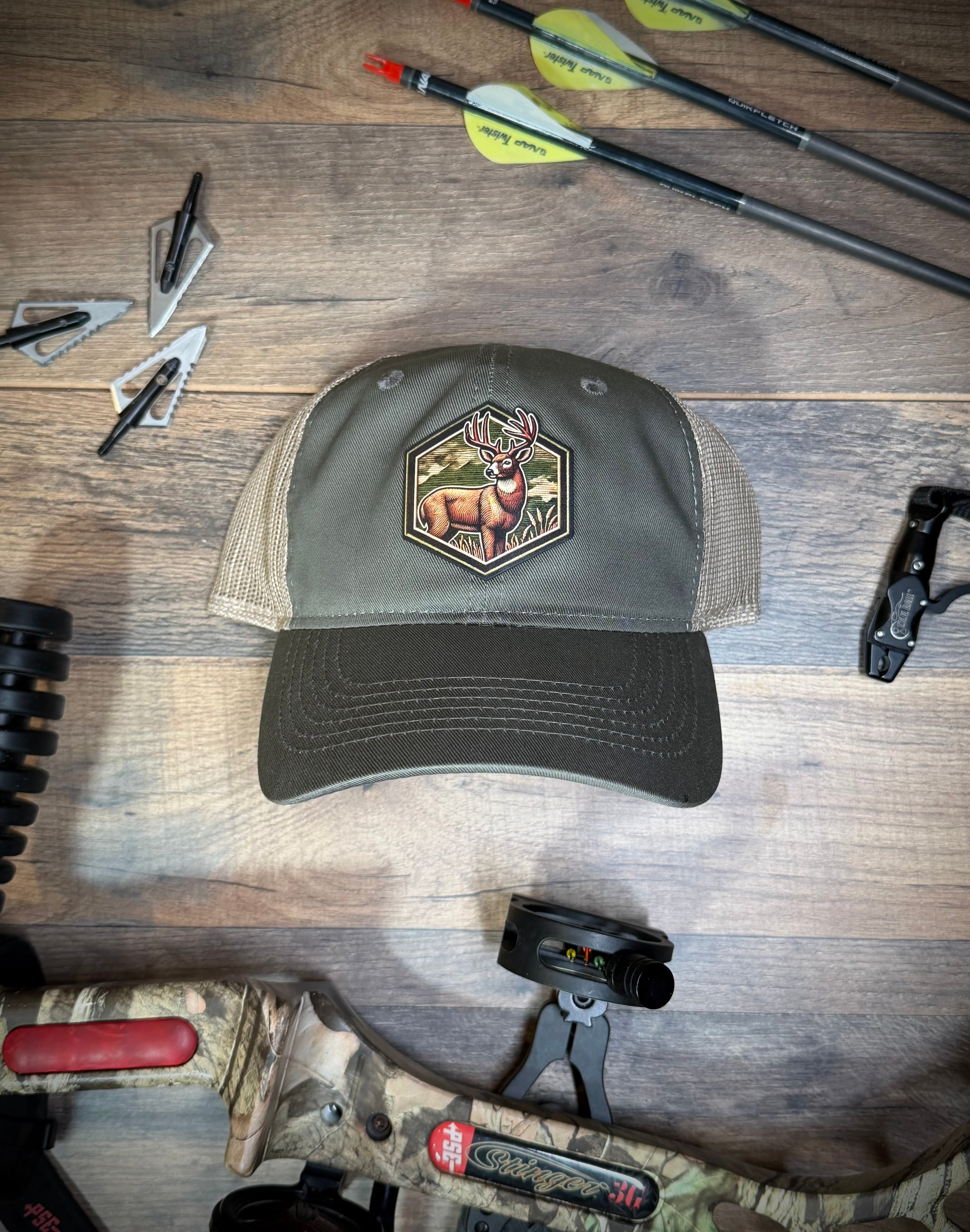 Cap with deer emblem on a wooden surface with hunting equipment
