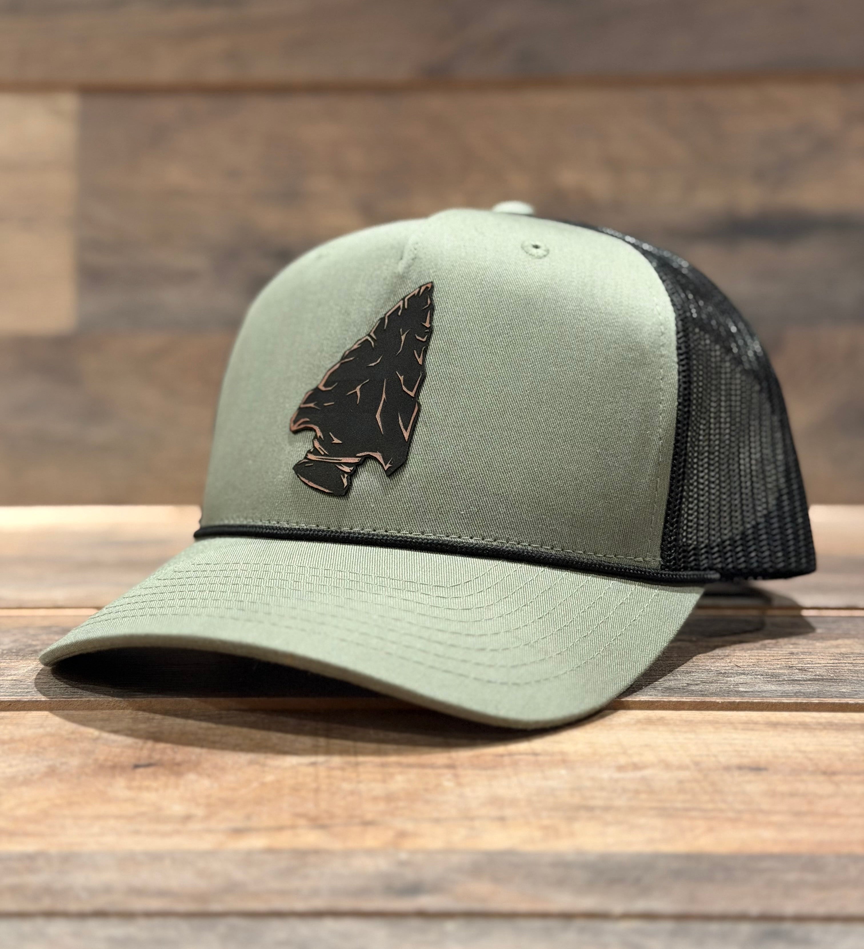 Green and black cap with an arrowhead design on a wooden surface