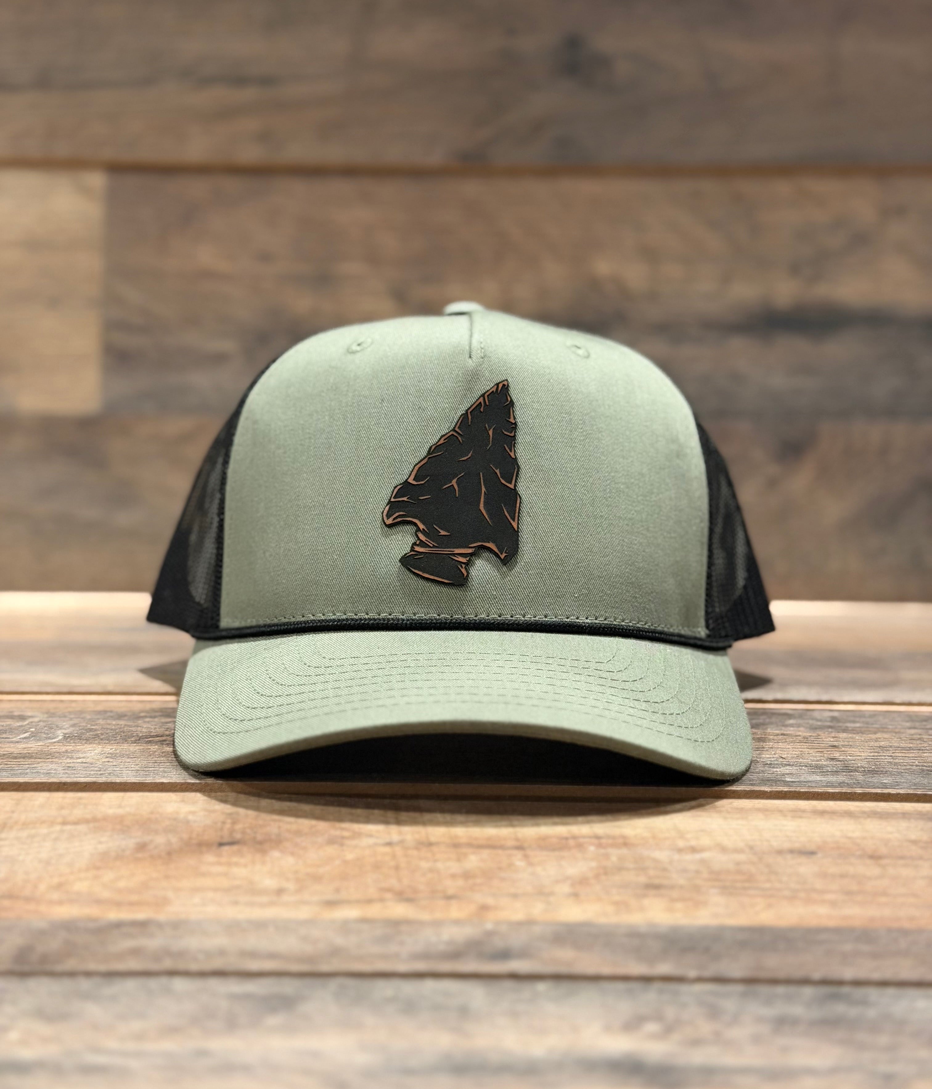 Green and black cap with an arrowhead design on a wooden surface