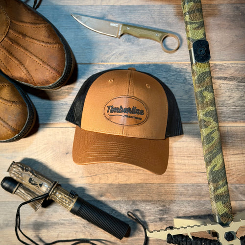 Brown cap with Timberline logo, knife, and other outdoor gear on a wooden surface