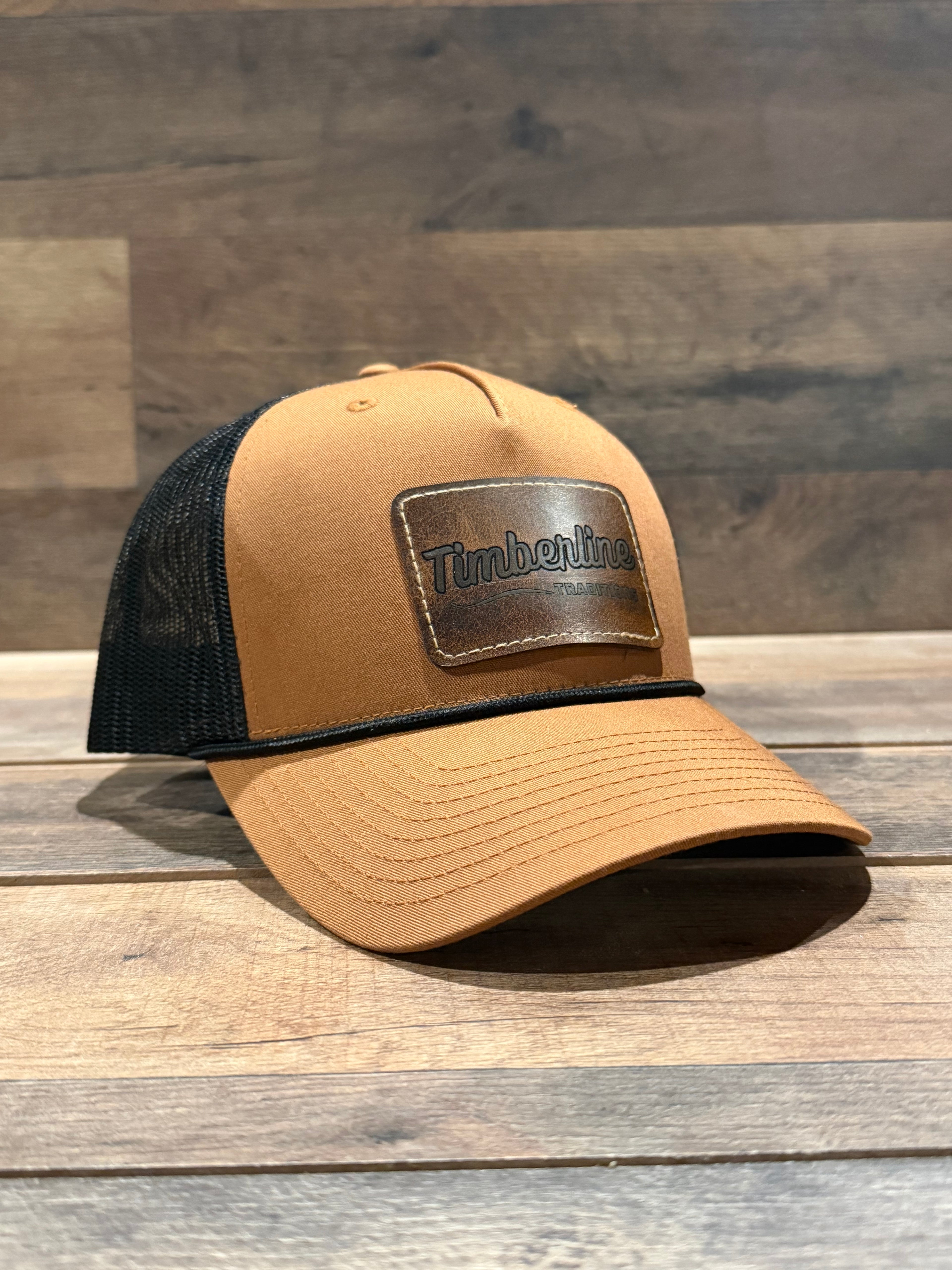 Tan and black cap with Timberland logo on a wooden surface