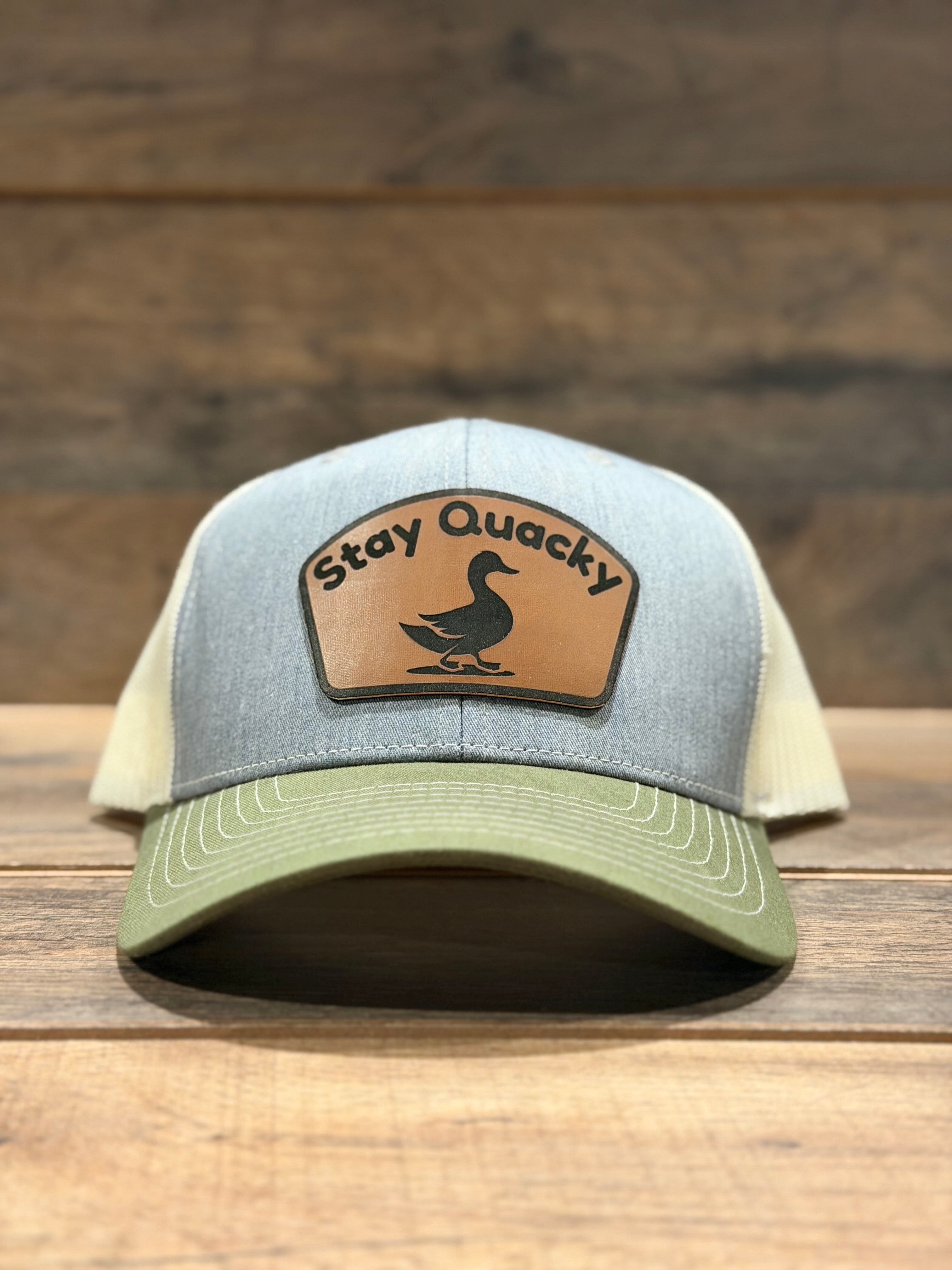 Trucker hat with 'Stay Quack' patch on a wooden surface