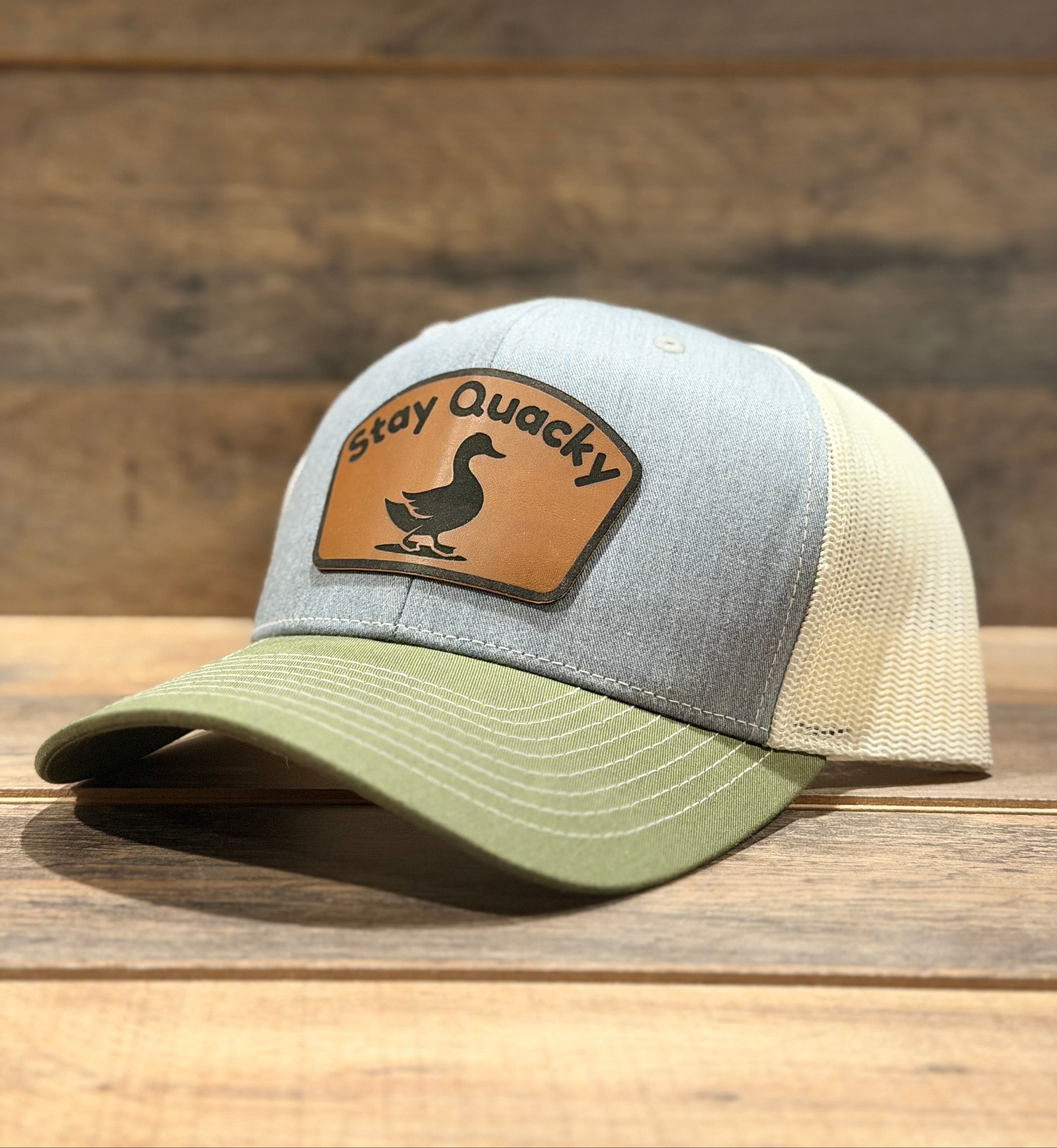 Gray and green cap with a leather patch on a wooden surface