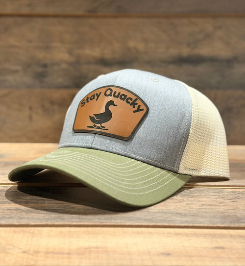 Gray and green cap with a leather patch on a wooden surface