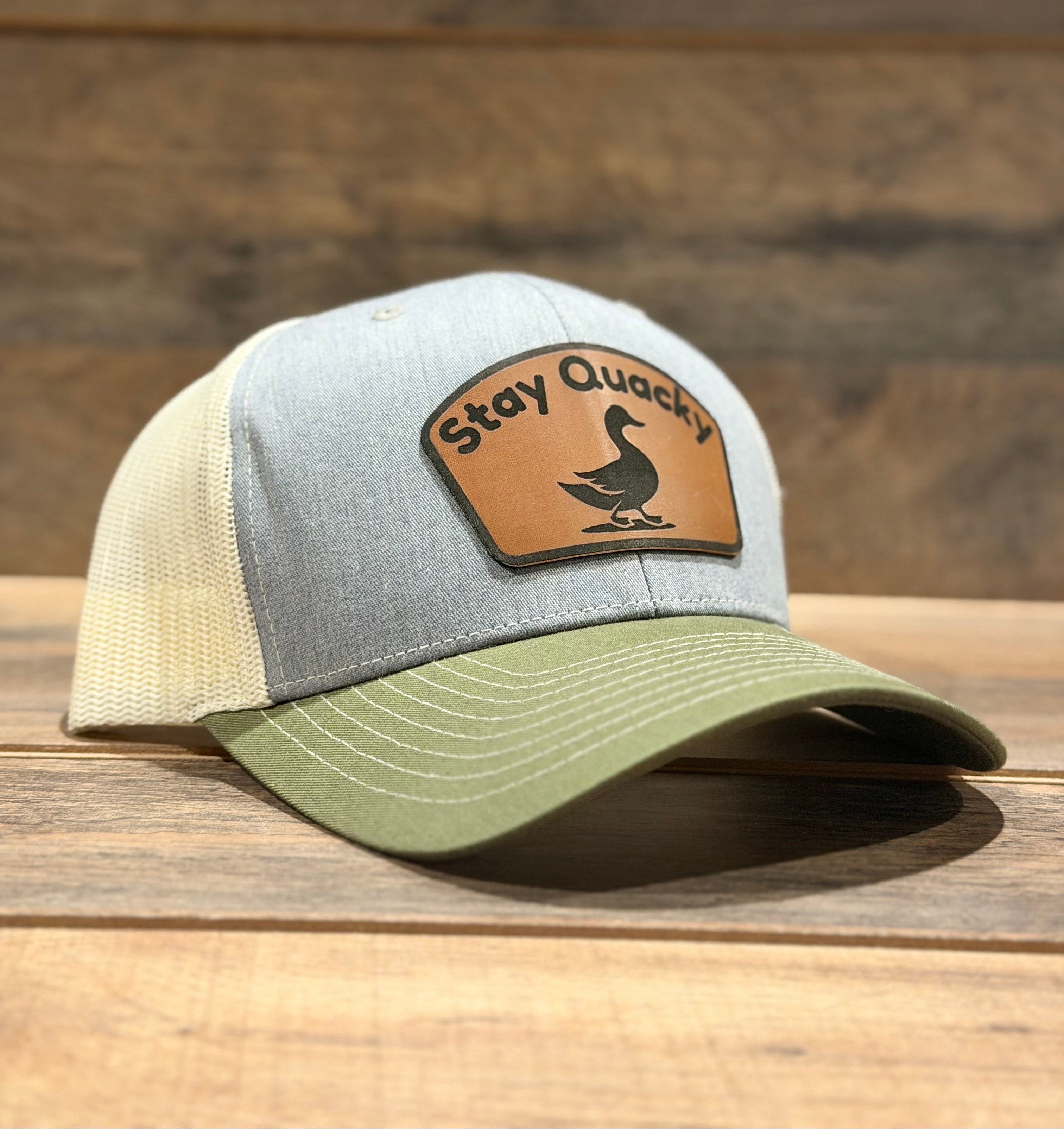 Trucker hat with 'Stay Quack' patch on a wooden surface