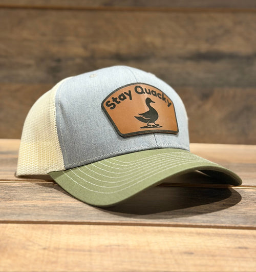 Trucker hat with 'Stay Quack' patch on a wooden surface